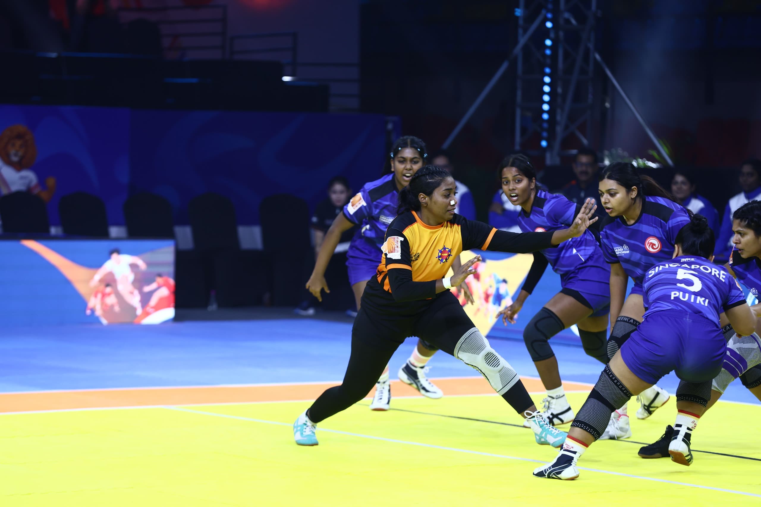 A Malaysia raider takes on Singapore's defence in the women's match at the Commonwealth Kabaddi Championship in Ahmedabad